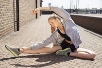 Runner stretching on walkway, Wapping, London — Stock Photo