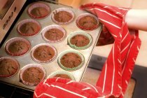 Imagem cortada de menina removendo cupcakes do forno — Fotografia de Stock