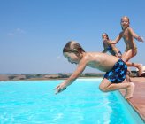 Três pessoas pulando na piscina — Fotografia de Stock