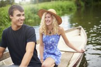 Parejas jóvenes en bote de remos en el río rural - foto de stock