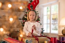 Menina embrulhando presentes de Natal em casa — Fotografia de Stock