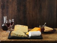 Stilton, goats cheese, red leicester and cheddar with red wine and crackers — Stock Photo