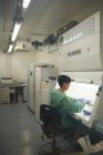 Scientist working behind screen of scientific machine — Stock Photo