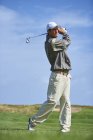 Vista anteriore a tutta lunghezza del golfista che tiene golf club prendendo golf swing — Foto stock