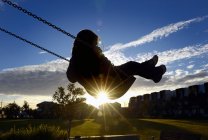 Jeune fille sur swing au coucher du soleil — Photo de stock