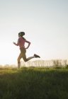 Young female runner listening to headphones whilst running — Stock Photo