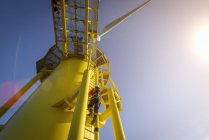 Engineers climbing wind turbine from boat at offshore windfarm, low angle view — Stock Photo
