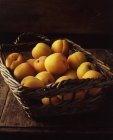 Wicker basket of ripe yellow peaches — Stock Photo