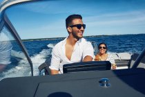 Young man steering boat with woman in background, Gavle, Sweden — Stock Photo