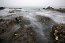 Lavado de agua sobre rocas en la playa - foto de stock