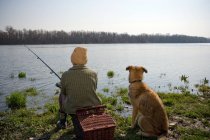 Хлопчик риболовля з собакою — стокове фото