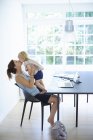 Mid adult woman holding up and kissing toddler daughter — Stock Photo
