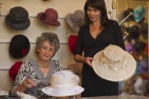 Milliner adjusting hat for customer in shop — Stock Photo