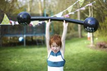 Young boy lifting pretend barbell, outdoors — Stock Photo
