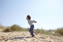 Joven chico volando cometa en la playa - foto de stock