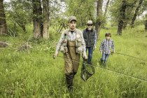 Front view of multi generation family in field carrying fishing rods — Stock Photo