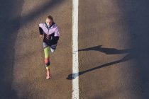 Vista de ángulo alto del corredor femenino corriendo por la carretera de la ciudad - foto de stock
