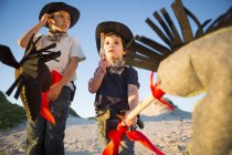 Two brothers dressed as cowboys with toy gun and hobby horses — Stock Photo