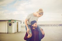 Mid adult woman getting shoulder ride from boyfriend on rooftop parking lot — Stock Photo