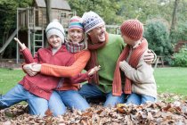 Portrait of family, sitting in autumn leaves — Stock Photo