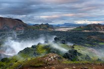 Rocky landscape with geothermal steam under cloudy sky — Stock Photo