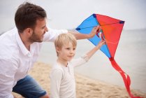Padre e figlio giocare aquilone sulla spiaggia — Foto stock