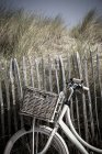 Крупним планом велосипед проти паркану з піщаною дюною — стокове фото