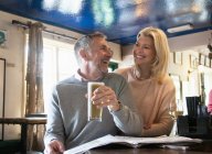 Casal rindo e lendo jornal no pub — Fotografia de Stock