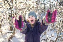 Jovencita riendo, con los brazos extendidos, en un paisaje nevado - foto de stock