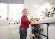 Мальчик стоит на стуле на кухне — стоковое фото