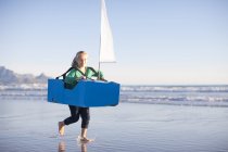 Fille courir avec bateau jouet le long de la plage — Photo de stock
