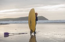 Giovane donna in spiaggia con kayak da mare, Polzeath, Cornovaglia, Inghilterra — Foto stock