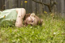 Menina deitada na grama do jardim sonhando acordado — Fotografia de Stock