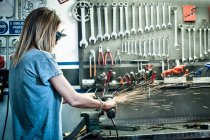 Female mechanic grinding metal in workshop — Stock Photo