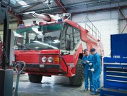 Engineers with fire engine in truck repair factor — Stock Photo