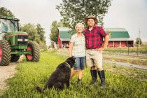Madre e figlio con cane in fattoria guardando la macchina fotografica sorridente — Foto stock