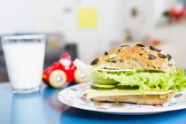 Бутерброд, склянка молока та іграшковий автомобіль на столі — стокове фото