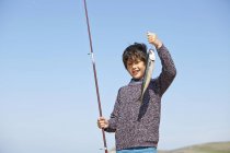 Young boy holding up fishing rod and fish — Stock Photo