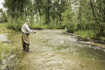 Homme portant des échassiers cheville profondément dans la pêche en eau dans la rivière — Photo de stock