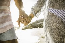Casal segurando as mãos enquanto caminhava na praia — Fotografia de Stock