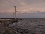 Windkraftanlagen an der Küste mit bewölktem Himmel bei Sonnenaufgang — Stockfoto