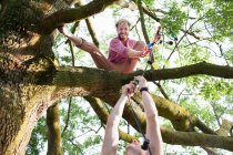 Молоді чоловіки передають декоративне світло другу в дереві на вечірці парку заходу сонця — стокове фото