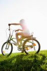 Fille à vélo dans l'herbe — Photo de stock