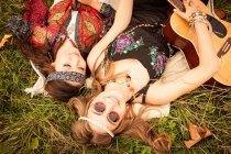 Hippy mujeres jóvenes que yacen en el campo con la guitarra - foto de stock