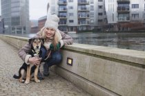 Retrato de mulher adulta média e seu cão na beira do rio da cidade — Fotografia de Stock