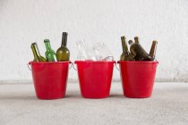 Три ведра для переработки в гараже с зелеными, коричневыми и прозрачными бутылками — стоковое фото