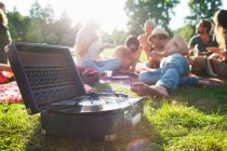Amigos adultos relaxando e ouvindo o deck de gravação na festa do parque ao pôr do sol — Fotografia de Stock