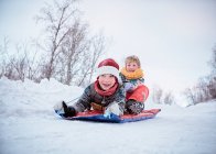 Low angle view of two brothers on toboggan on snow covered hill, Hemavan,Sweden — Stock Photo