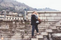 Casal jovem abraçando passos da parede do porto, Lago de Como, Itália — Fotografia de Stock
