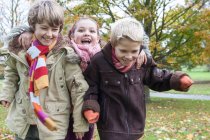 Tre bambini che corrono nel parco, ridendo — Foto stock